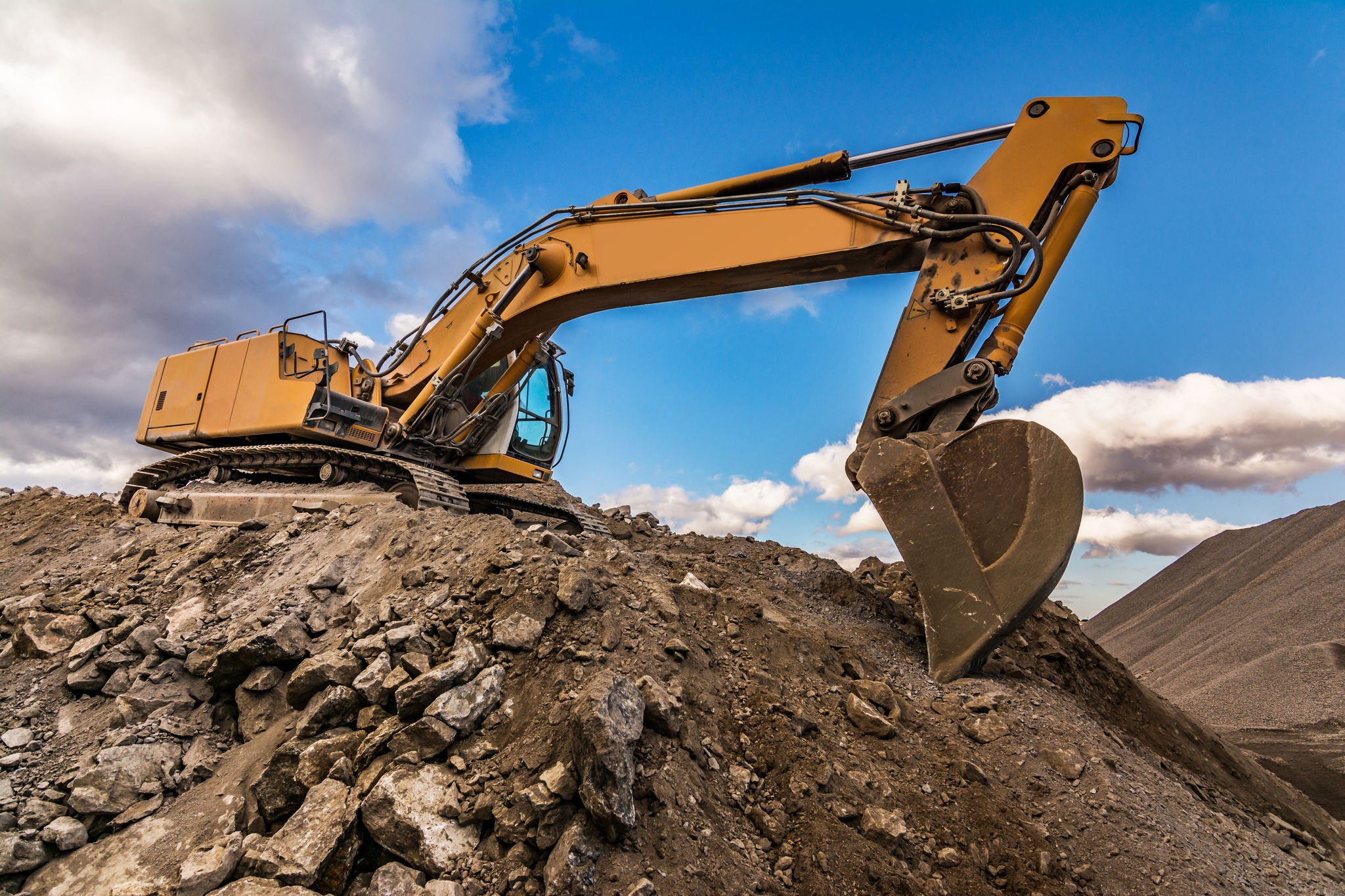 QM Industry, Excavator performing stone extraction work in an open pit stone mine