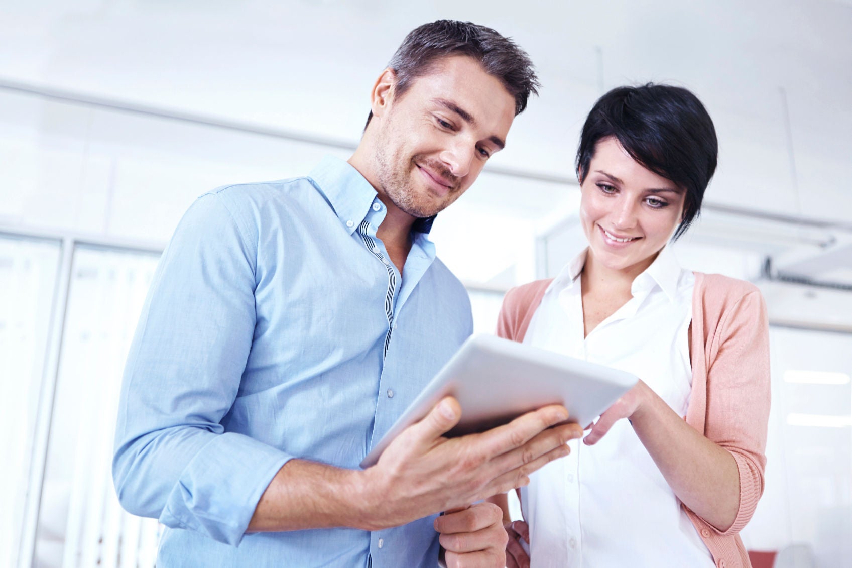 People, Two businesspeople standing together in the office and looking at a digital tablet